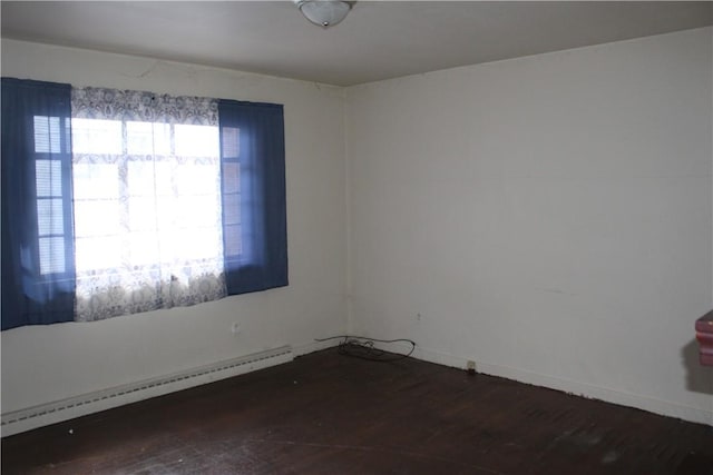 spare room featuring baseboard heating and dark wood-type flooring