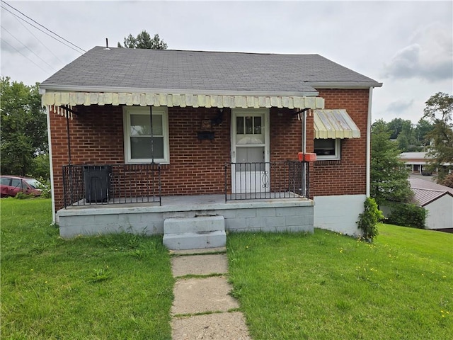 bungalow with brick siding, a shingled roof, and a front yard