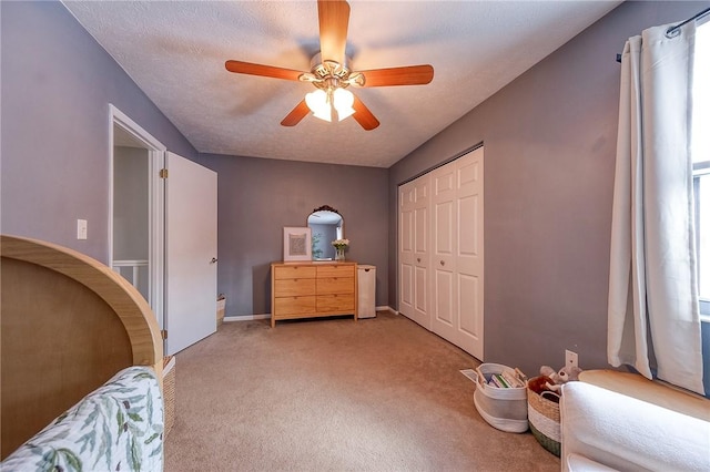 carpeted bedroom with a closet, ceiling fan, and a textured ceiling