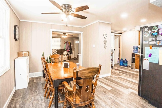 dining space with light wood-type flooring, crown molding, and a barn door