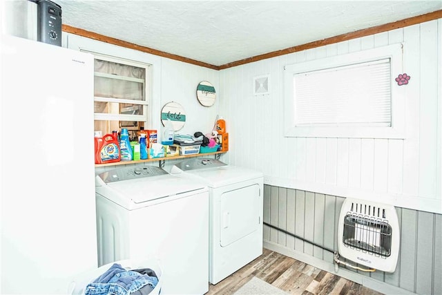 washroom with heating unit, a textured ceiling, washer and dryer, and light hardwood / wood-style flooring