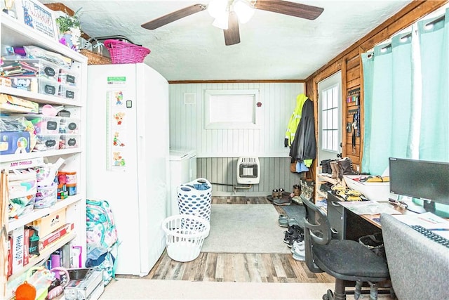 office area with heating unit, light hardwood / wood-style floors, and ceiling fan