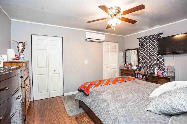 bedroom featuring a wall unit AC, ceiling fan, multiple closets, dark hardwood / wood-style flooring, and ornamental molding