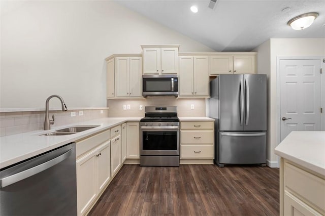 kitchen featuring stainless steel appliances, dark hardwood / wood-style flooring, cream cabinetry, sink, and decorative backsplash