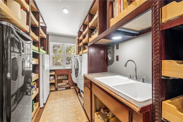 clothes washing area with washing machine and dryer, sink, and light tile patterned floors