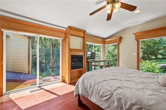 bedroom featuring a large fireplace, lofted ceiling, access to outside, and wood-type flooring