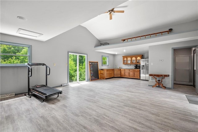 exercise room with ceiling fan, light hardwood / wood-style floors, a healthy amount of sunlight, and lofted ceiling