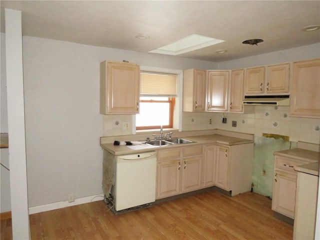 kitchen featuring light wood-style flooring, white dishwasher, light countertops, under cabinet range hood, and a sink