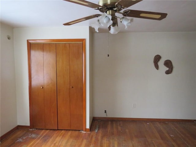 unfurnished bedroom with dark wood-style floors, a closet, ceiling fan, and baseboards