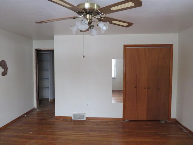 unfurnished bedroom with baseboards, visible vents, a ceiling fan, dark wood-style floors, and a closet