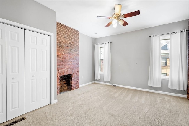 unfurnished living room with ceiling fan, a brick fireplace, and light colored carpet