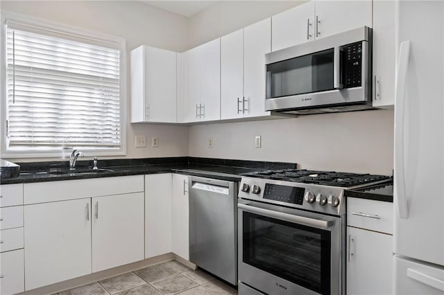 kitchen featuring light tile patterned flooring, sink, stainless steel appliances, and white cabinetry