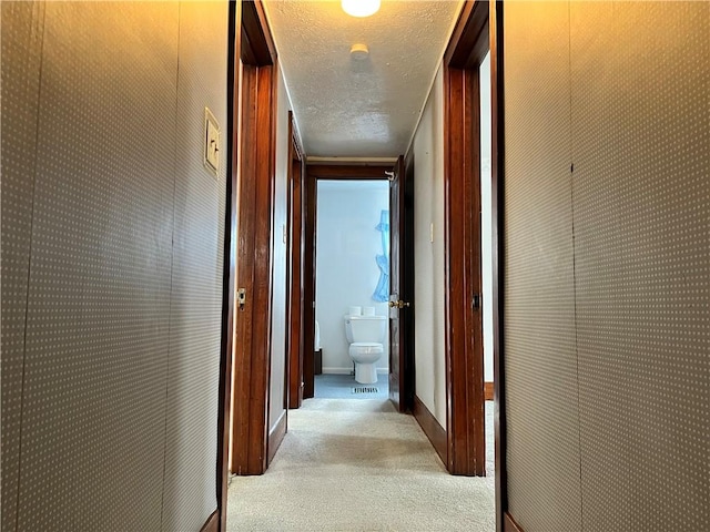 hallway featuring a textured ceiling and light colored carpet