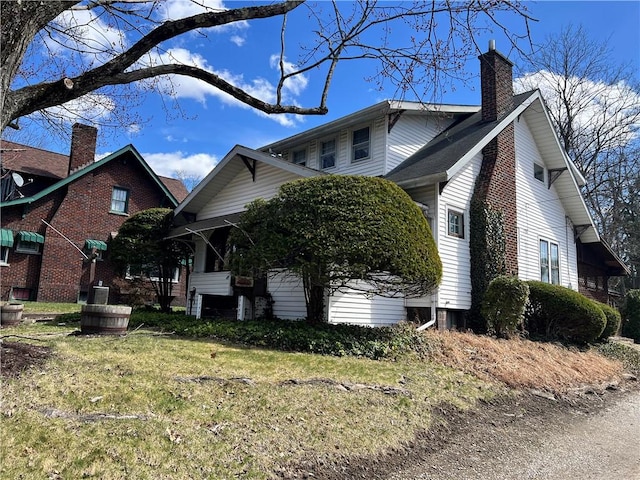 view of property exterior with a lawn and a chimney