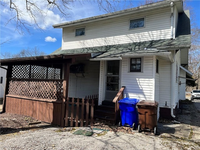 back of property featuring fence, roof with shingles, and entry steps