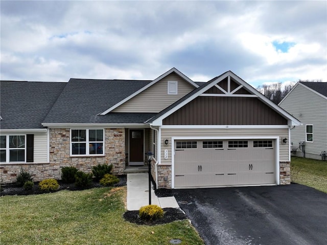 craftsman-style home with a garage, a shingled roof, aphalt driveway, a front lawn, and board and batten siding