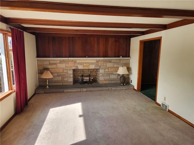 unfurnished living room with carpet floors, beamed ceiling, and a fireplace