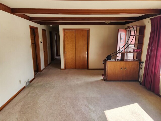 unfurnished room with light carpet and beam ceiling