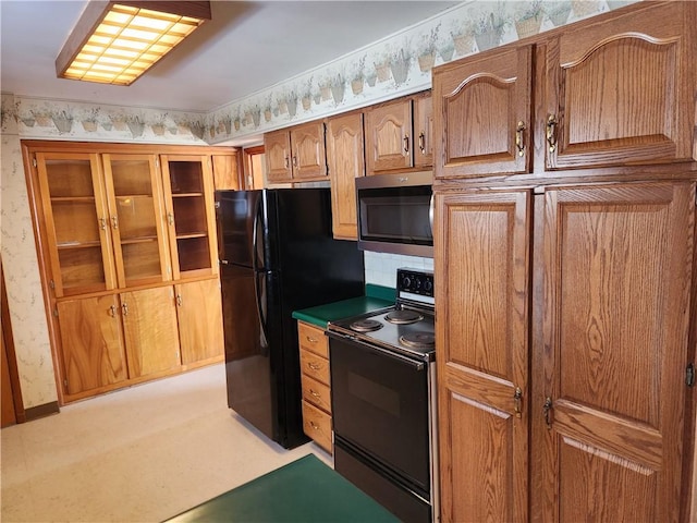 kitchen with range with electric cooktop, light colored carpet, and black fridge