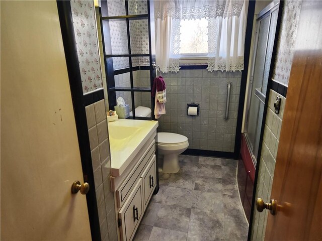 bathroom with tile walls, vanity, toilet, and walk in shower