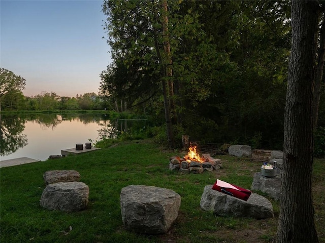 yard at dusk with a water view and an outdoor fire pit