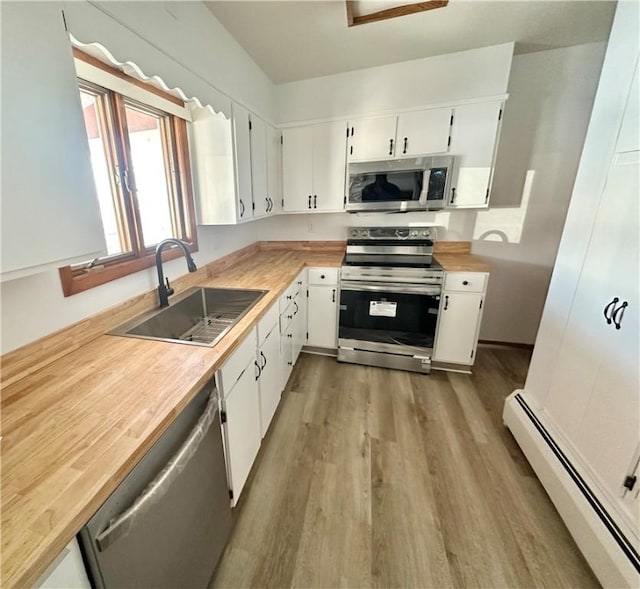 302 S Main St, Masontown, PA 15461 - kitchen featuring stainless steel appliances, a sink, baseboard heating, wood finished floors, and white cabinets