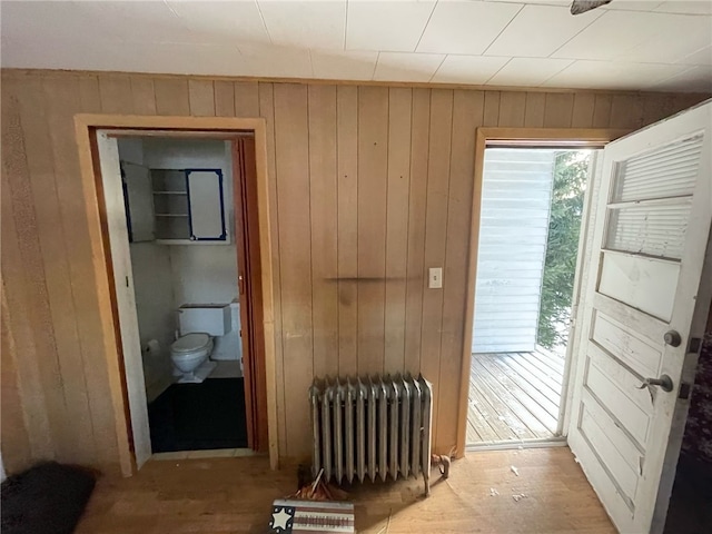 entryway featuring radiator, light hardwood / wood-style flooring, and wooden walls