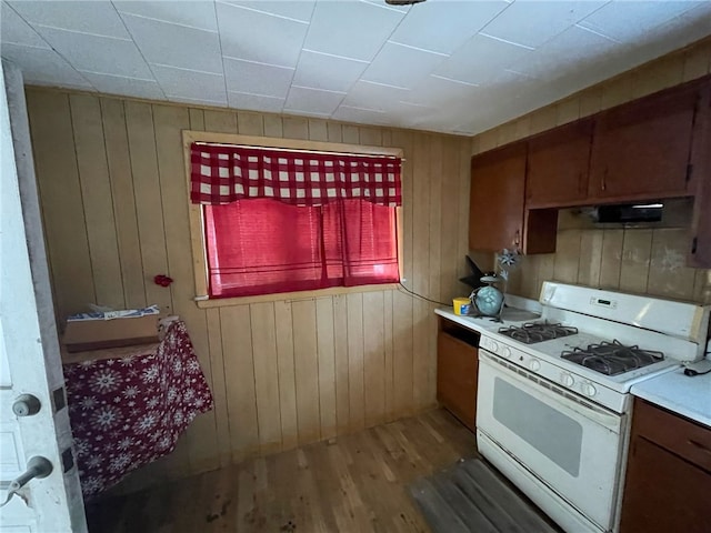 kitchen featuring white gas range, wood walls, and dark hardwood / wood-style floors