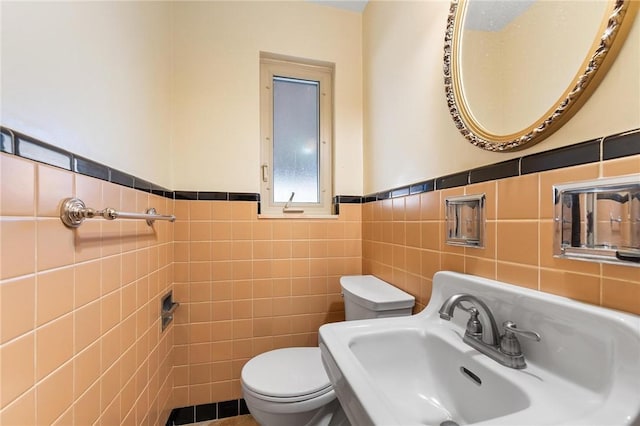 bathroom with tile walls, sink, and toilet