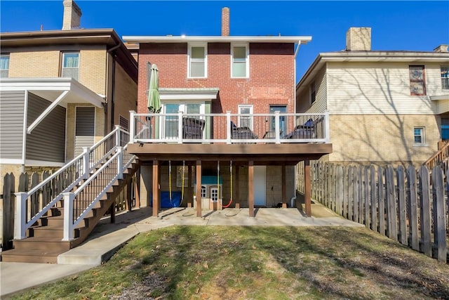 back of property featuring a deck, a patio, and a lawn