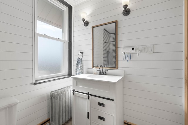 bathroom with radiator, vanity, and wood walls