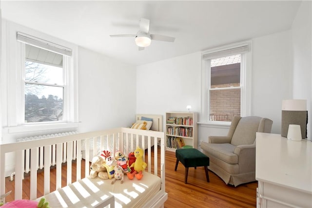 bedroom with ceiling fan, wood-type flooring, and radiator heating unit