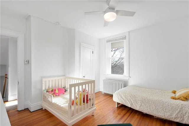 bedroom with radiator heating unit, ceiling fan, and wood-type flooring