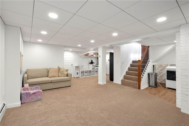 living room featuring a drop ceiling, a baseboard radiator, and light carpet