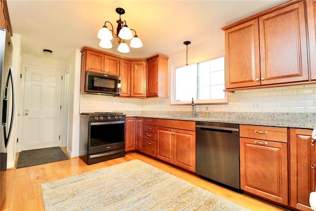 1219 Minnesota Ave, Natrona Hts/Harrison Twp, PA 15065 - kitchen with light stone counters, a sink, brown cabinets, light wood-style flooring, and appliances with stainless steel finishes