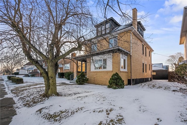 view of front of property featuring a chimney and brick siding