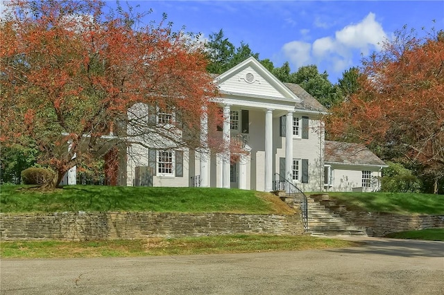 neoclassical home featuring a front yard