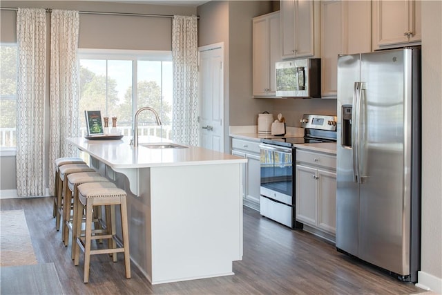 kitchen with white cabinets, an island with sink, stainless steel appliances, light countertops, and a sink