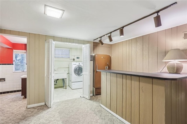 interior space with light carpet, washer / dryer, a sink, and rail lighting