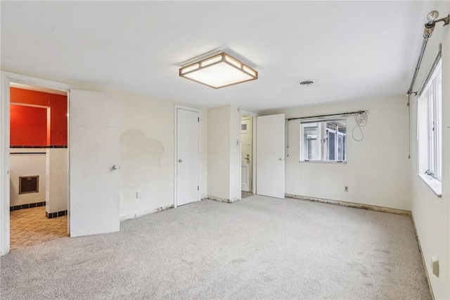 empty room with carpet, visible vents, and a healthy amount of sunlight