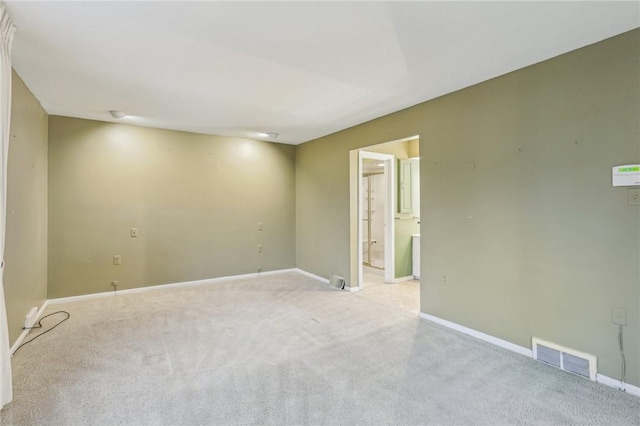 unfurnished room featuring light colored carpet, visible vents, and baseboards