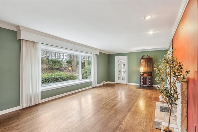 unfurnished living room with baseboards, crown molding, and wood finished floors