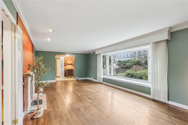 unfurnished living room with ornamental molding, baseboards, and wood finished floors