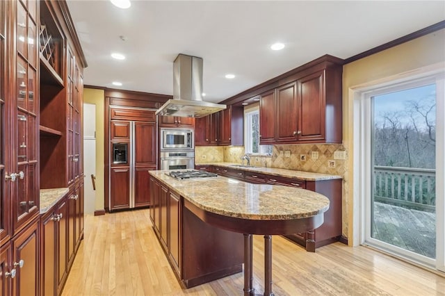 kitchen featuring built in appliances, light stone counters, a kitchen island, light wood finished floors, and island exhaust hood