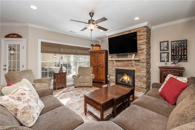 living room with ceiling fan, ornamental molding, and a stone fireplace