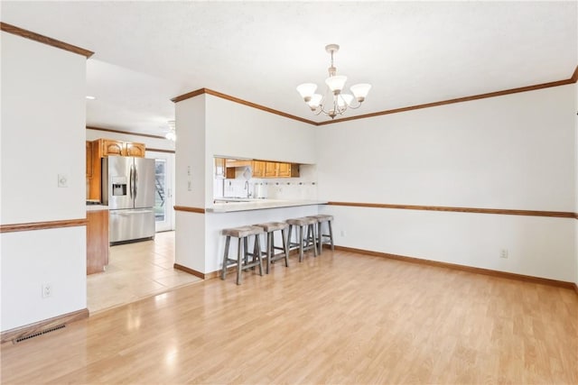 interior space with light wood-type flooring, an inviting chandelier, crown molding, and sink