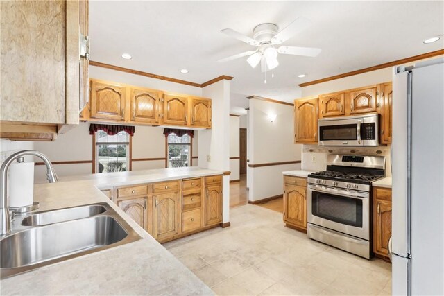 kitchen with kitchen peninsula, stainless steel appliances, sink, ceiling fan, and crown molding