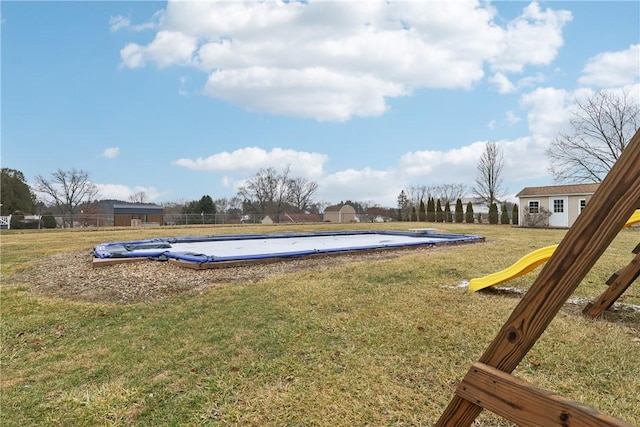 view of yard featuring a covered pool, a playground, and an outbuilding