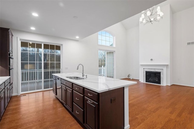 kitchen with a high end fireplace, pendant lighting, a sink, and light wood-style flooring