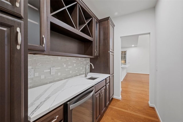 kitchen with open shelves, stainless steel dishwasher, a sink, dark brown cabinetry, and light stone countertops